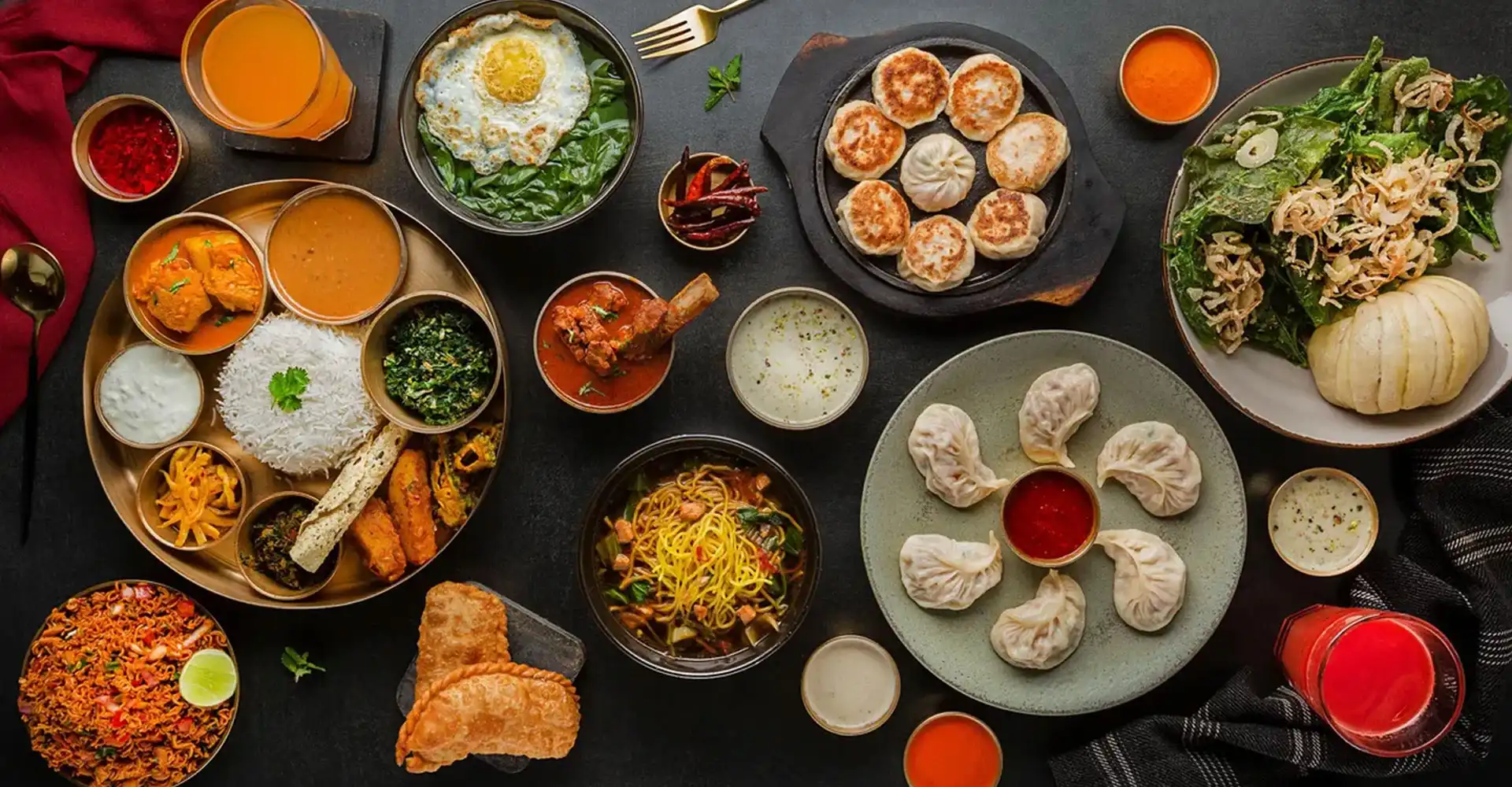 About us photo showing Nepali and Indian food spread including momos, curries, rice, and naan at MoMo Spot in Irving, TX